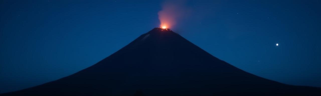 Dark silhouette of a volcano under a starry sky